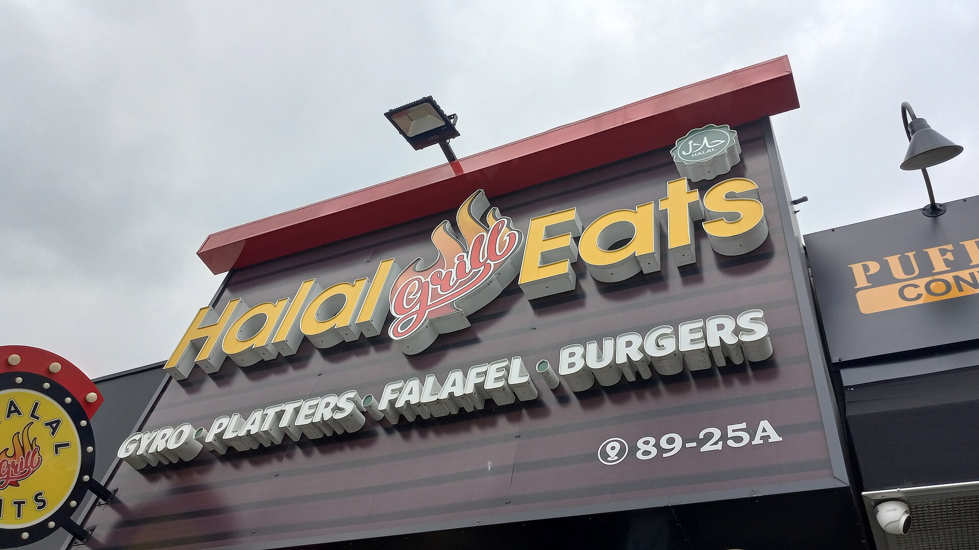 Shopfront sign of a halal grill restaurant showing the halal mark and menu categories